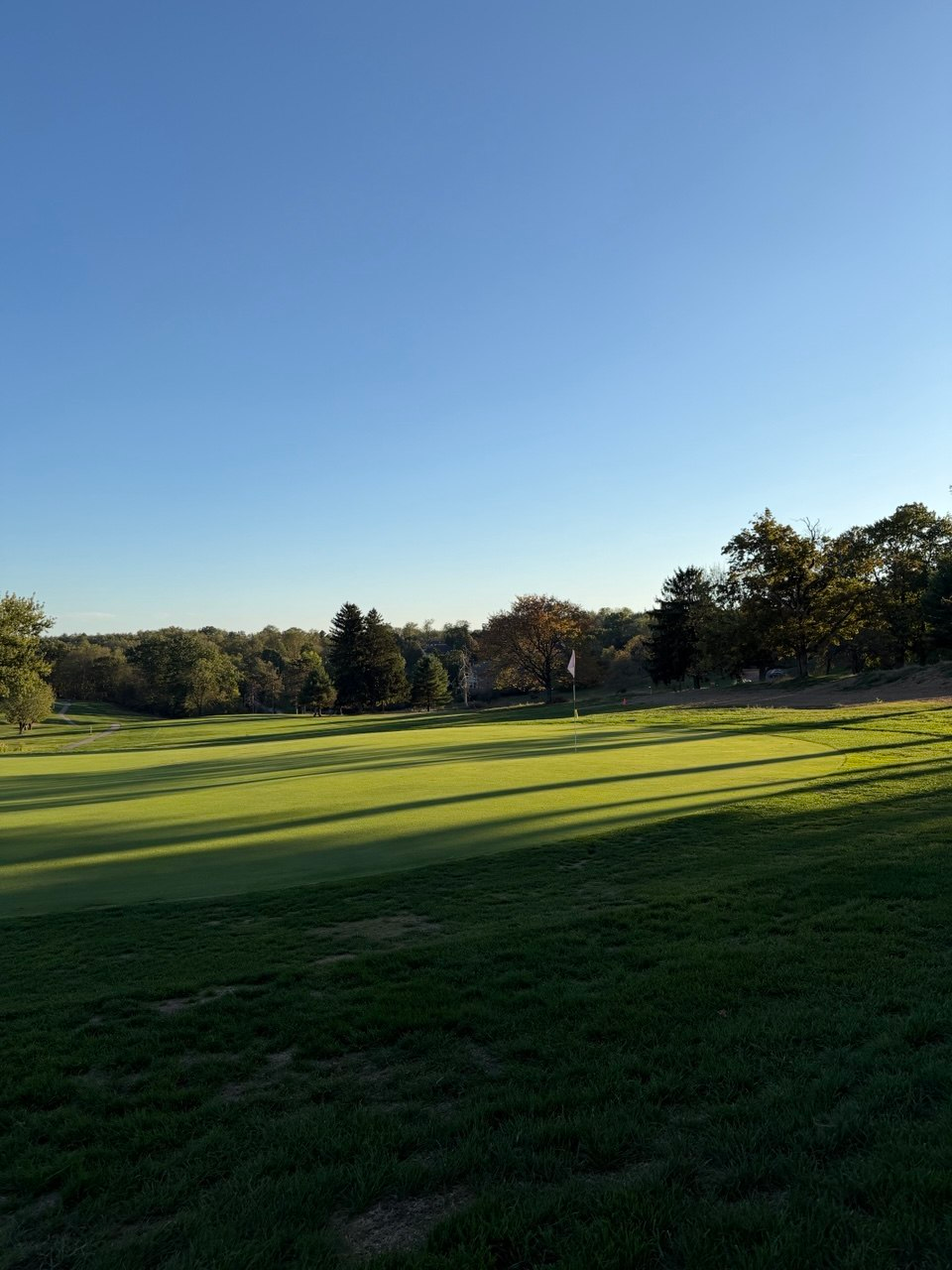 Golden hour shadows across a green at North Park Golf Course